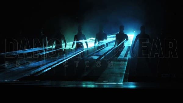 Multiple figures standing infront of laser beams