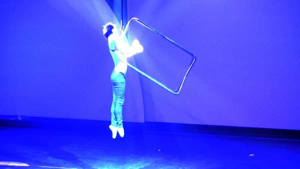 Aerial Cage Man hanging from an open cage on a rope